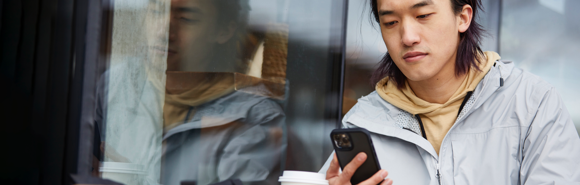 A man sitting outside a coffee shop looks at his phone